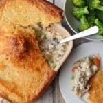 two plates with food on them next to a bowl of broccoli and bread