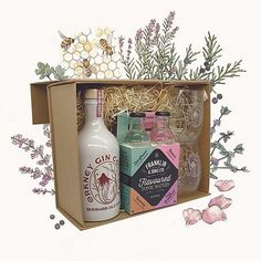 an open box with bottles and flowers on the inside is filled with lavenders, honey, gin