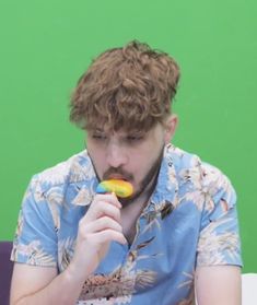 a young man eating a donut in front of a green screen