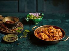 some food is sitting on a table with other dishes in the background and one bowl full of vegetables