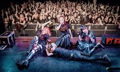 three people laying on the ground in front of an audience with their hands up to their chests