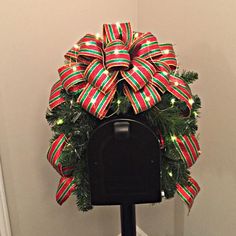 a mailbox decorated with red, green and gold christmas ribbon bow on it's front door