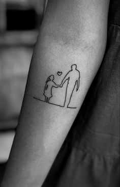 a man and woman holding hands on the arm with a small tattoo design on it