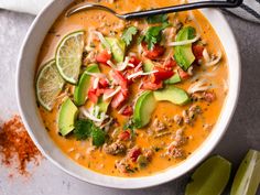 a white bowl filled with soup and topped with avocado