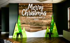 a merry christmas sign on the side of a wall in a room with wooden floors