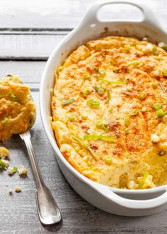 a casserole dish with broccoli and cheese in it next to a spoon