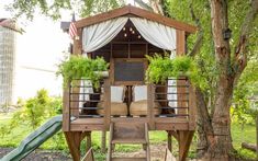 a small wooden structure with plants on top and a slide in the back ground next to it