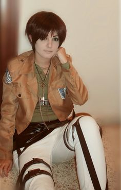 a woman sitting on the floor with her hand to her ear and wearing white pants