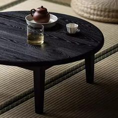 a wooden table with a tea pot on it and two cups sitting on the coffee table