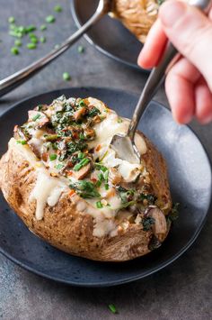 a person is spooning some food out of a baked potato on a black plate