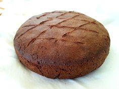 a round chocolate cake sitting on top of a white table cloth next to a knife