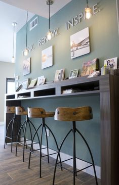 a row of bar stools in front of a counter with pictures on the wall