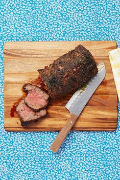 a meatloaf on a cutting board with a knife next to it and a napkin