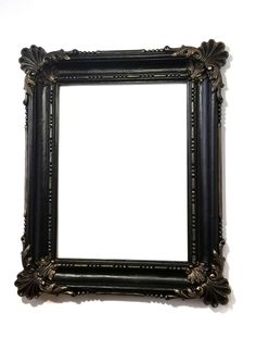 an ornate black framed mirror against a white wall with clippings on the edges