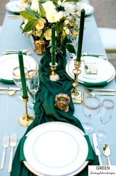 the table is set with plates, silverware and green napkins as well as flowers