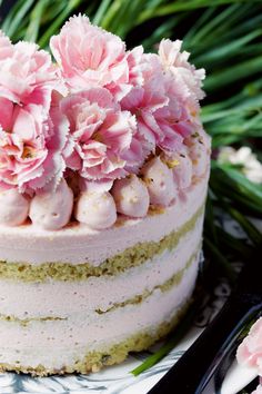 a close up of a cake on a plate with flowers in the middle and green leaves behind it