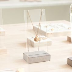 three different types of necklaces on display in clear acrylic cases with gold chains