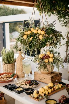 a table topped with lots of food next to a potted plant and vase filled with lemons