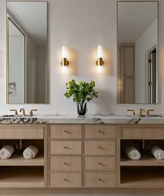 a bathroom with two sinks, mirrors and lights on the wall next to each other