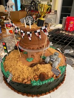 a cake that is sitting on top of a table with flags and dirt around it