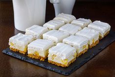 several pieces of cake sitting on a black plate next to a white cup and milk jug