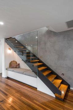 an empty room with wooden flooring and glass railings on the wall next to stairs