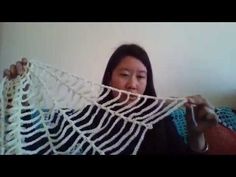 a woman is holding up a white crocheted shawl