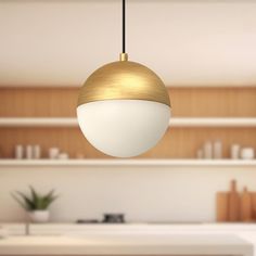 a white and gold pendant light hanging from a ceiling in a kitchen with wooden cabinets