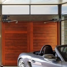 a silver sports car parked in front of a wooden garage door with two open doors