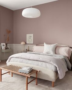 a bedroom with pink walls and white furniture