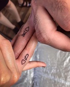 two people holding hands with tattoos on their fingers