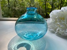 a blue vase sitting on top of a table next to a white carnation flower