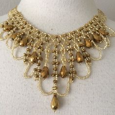 a gold necklace with lots of beads and chains on top of a mannequin