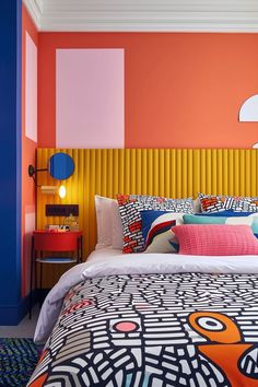 a bedroom with an orange, pink and blue color scheme on the wall behind the bed