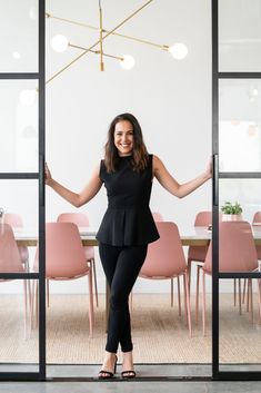 a woman standing in front of a glass door with her hands out and smiling at the camera