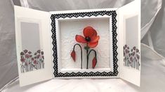 an open card with two red flowers in the middle and one black border around it