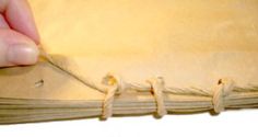 a hand is stitching the edges of an old book with twine and thread