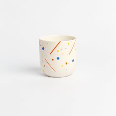 a white cup with orange and blue dots on it