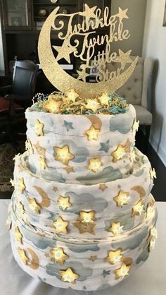 a three tiered cake with stars and moon decorations on the top, sitting on a table