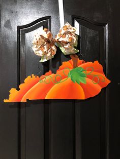 a door hanger with two pumpkins and a bow on it's head