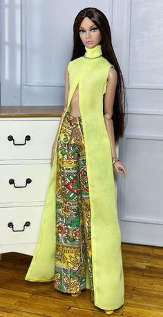 a barbie doll wearing a yellow dress and high heels standing in front of a dresser