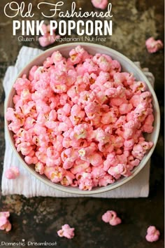 a bowl filled with pink popcorn sitting on top of a table