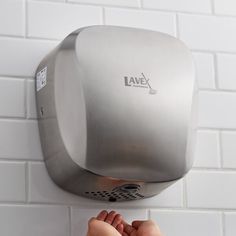 a person's foot is on the wall next to a silver soap dispenser