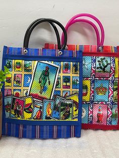 two colorful handbags sitting next to each other on top of a white tablecloth