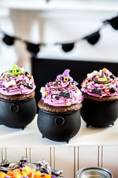 three black caulders with pink frosting and sprinkles on them