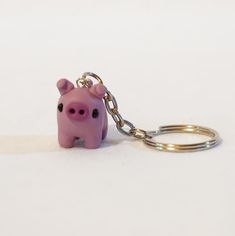 a pink pig keychain sitting on top of a white surface