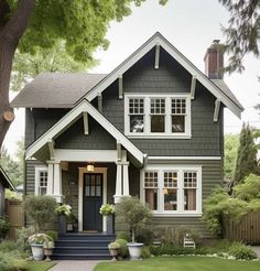 a gray house with white trim and two story windows on the second floor is surrounded by greenery