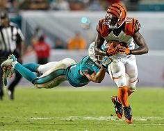 a football player is diving for the ball while being tackled by another player in an orange and white uniform