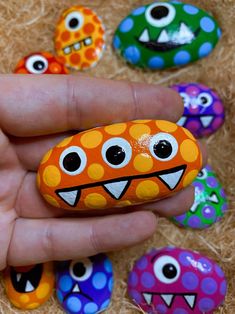 a hand is holding some colorful rocks with faces on them