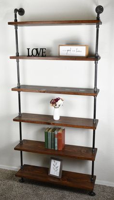 a book shelf with three shelves and two books on each shelf, in front of a white wall